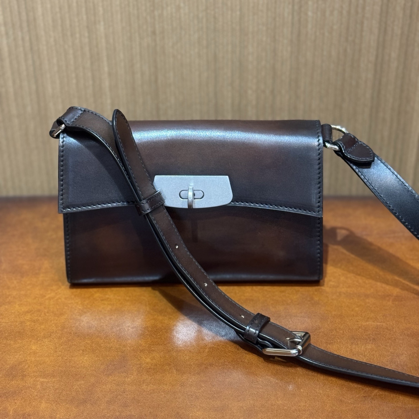 brown leather shoulder bag, possibly with a custom or unknown brand logo on the clasp