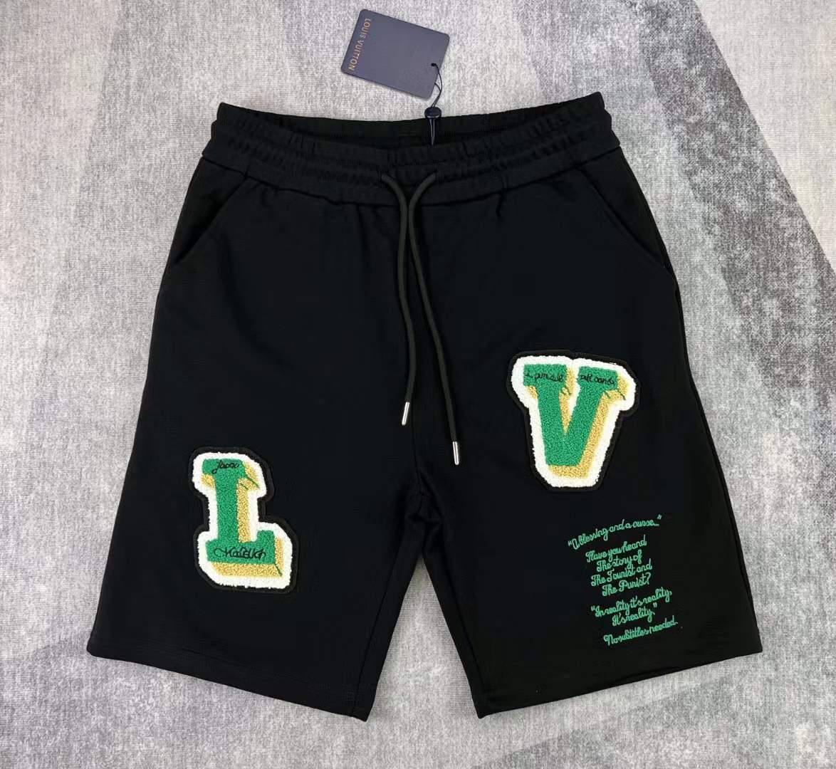 LV black shorts with green and yellow embroidered "L" and "V" patches