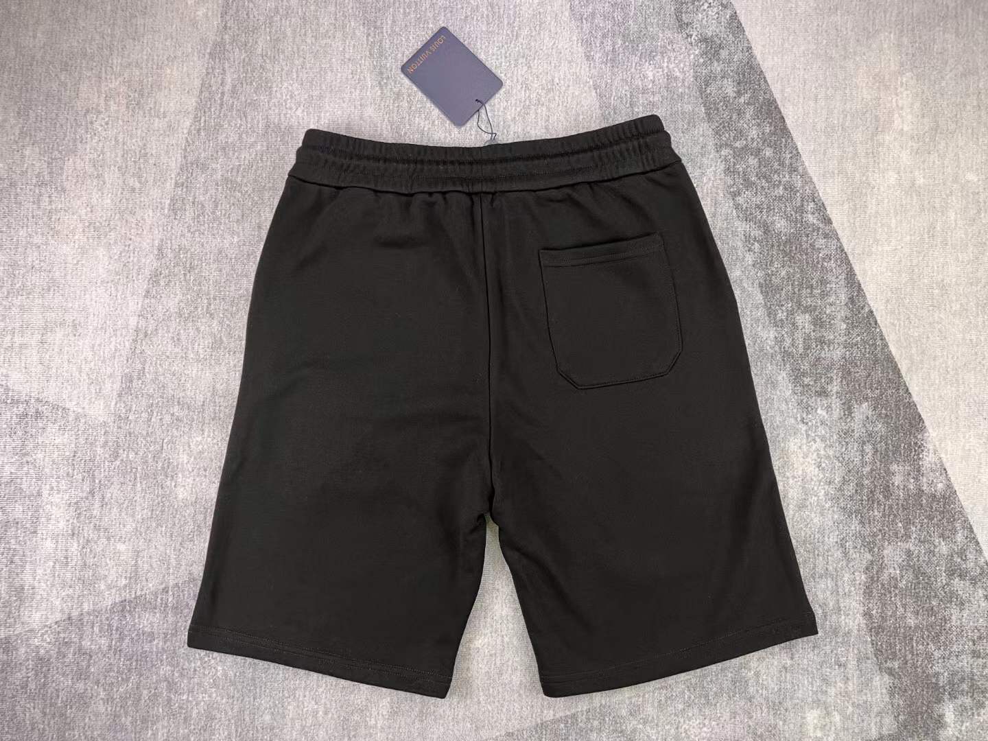 LV black shorts with green and yellow embroidered "L" and "V" patches