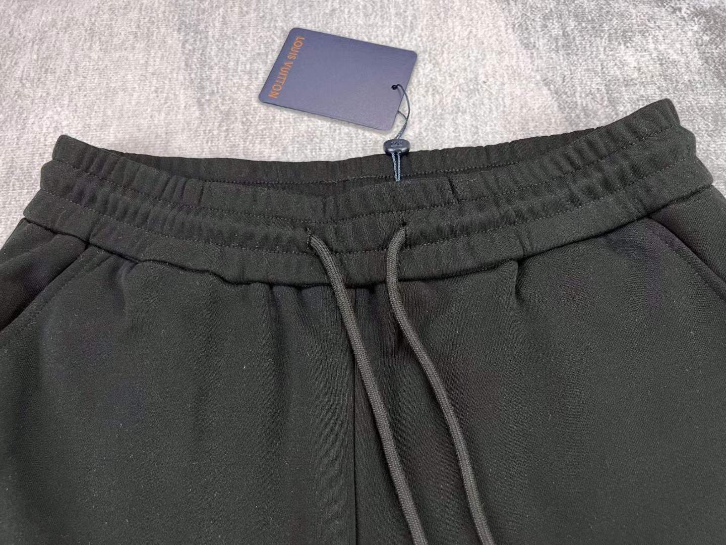 LV black shorts with green and yellow embroidered "L" and "V" patches