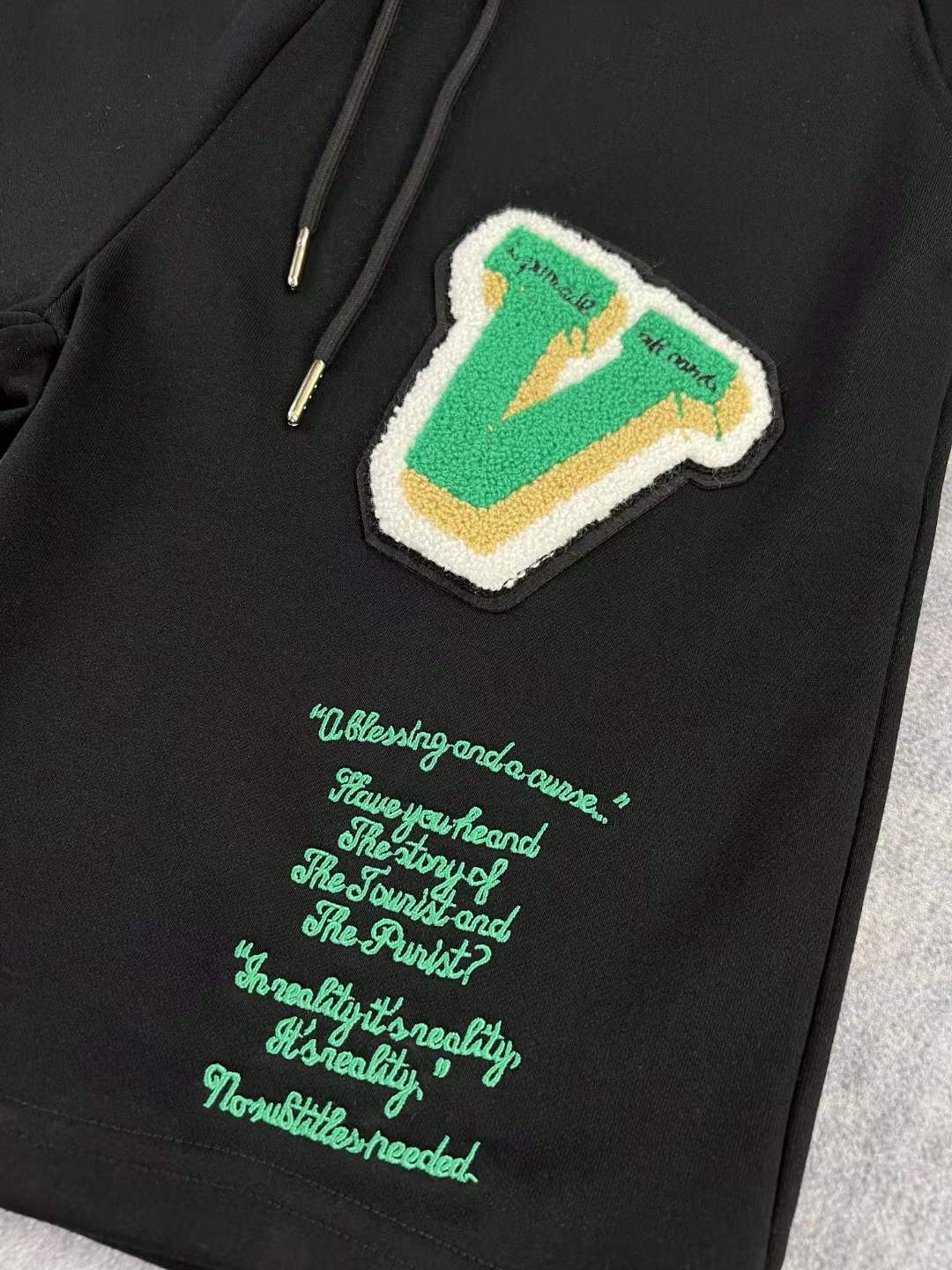 LV black shorts with green and yellow embroidered "L" and "V" patches