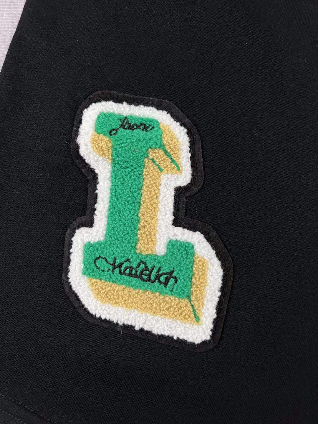 LV black shorts with green and yellow embroidered "L" and "V" patches