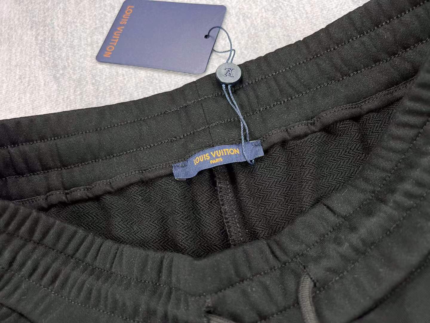 LV black shorts with green and yellow embroidered "L" and "V" patches