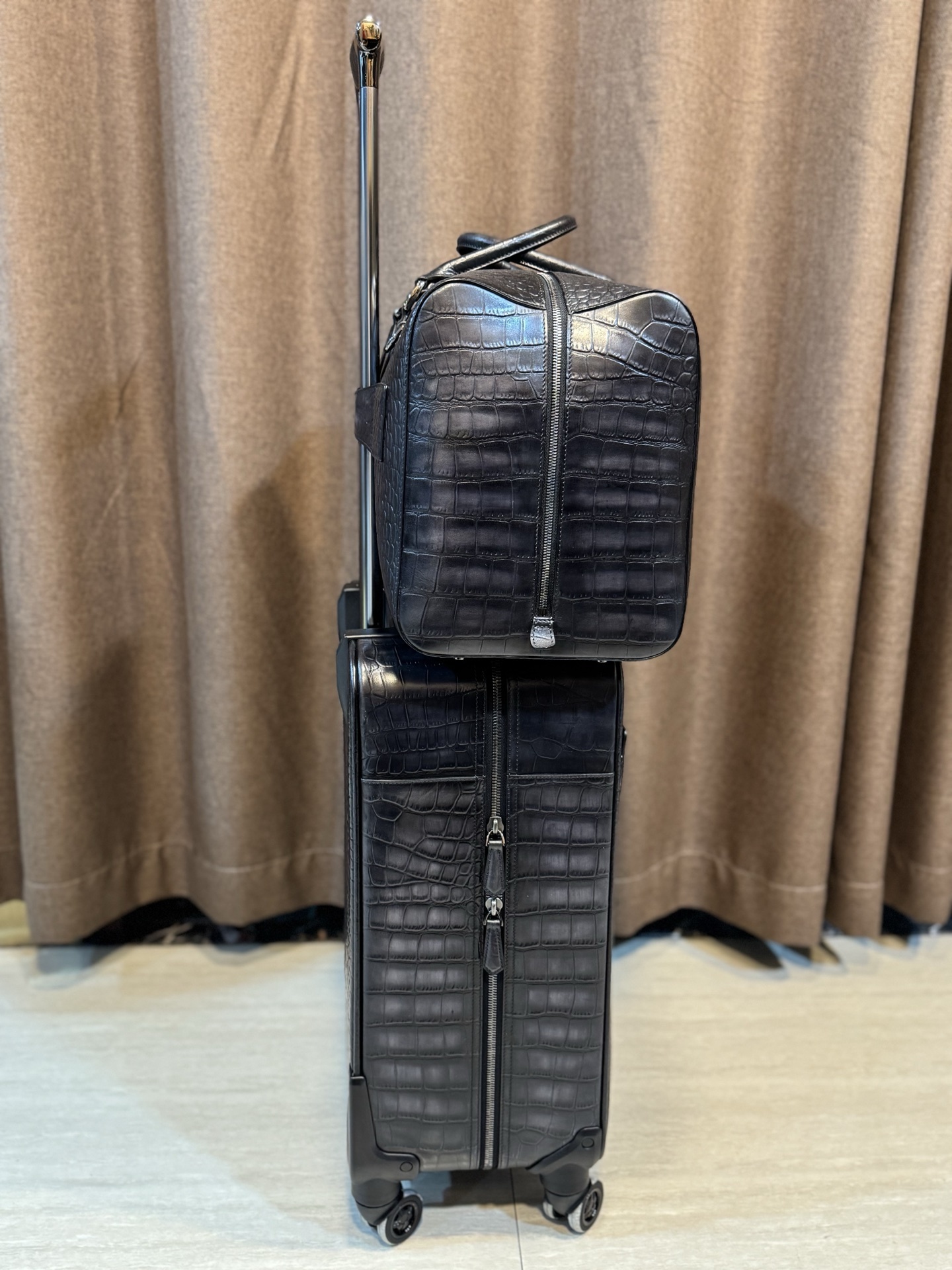 Berluti black crocodile-embossed leather luggage set including a wheeled suitcase and a duffel bag.