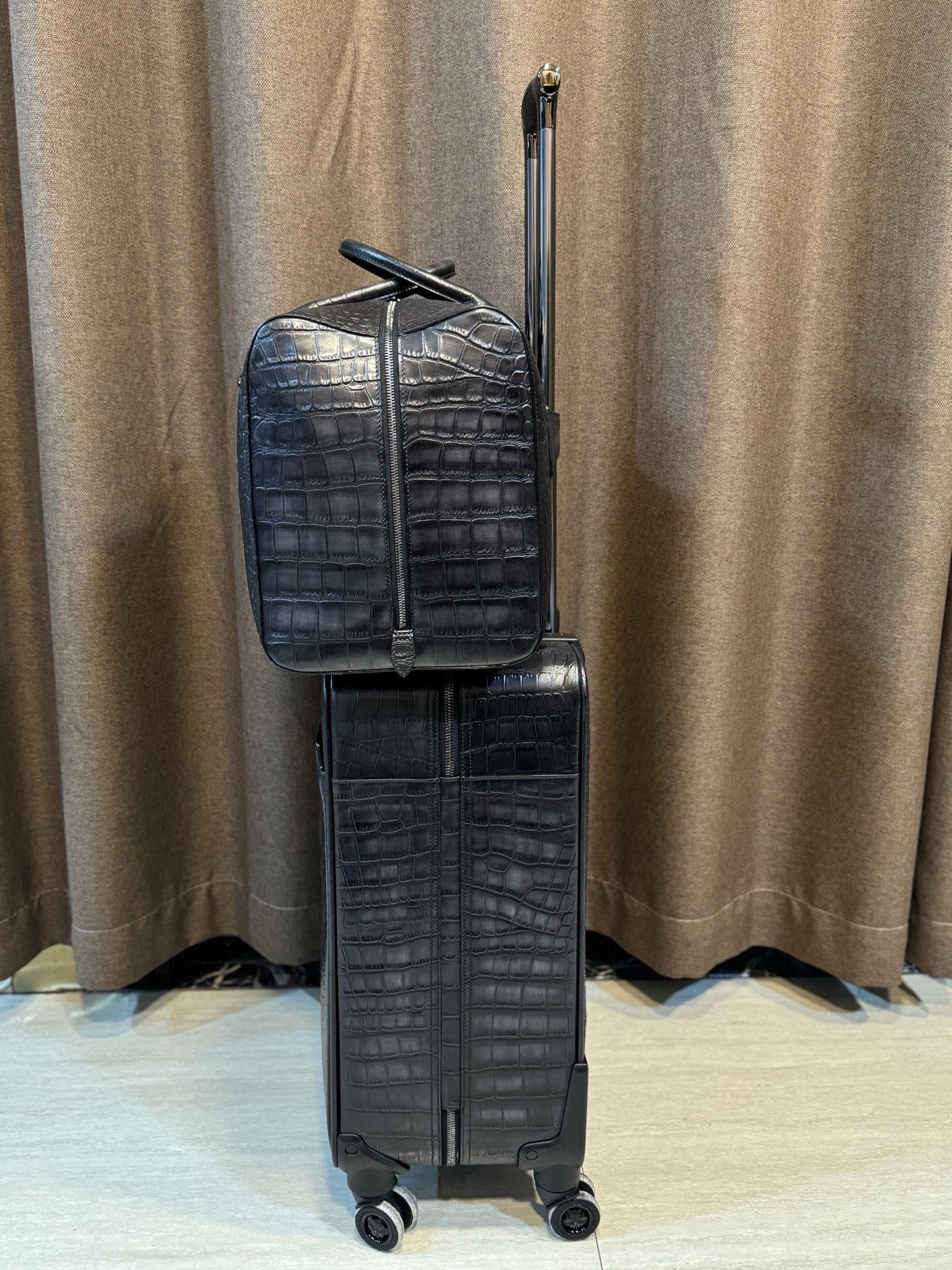 Berluti black crocodile-embossed leather luggage set including a wheeled suitcase and a duffel bag.