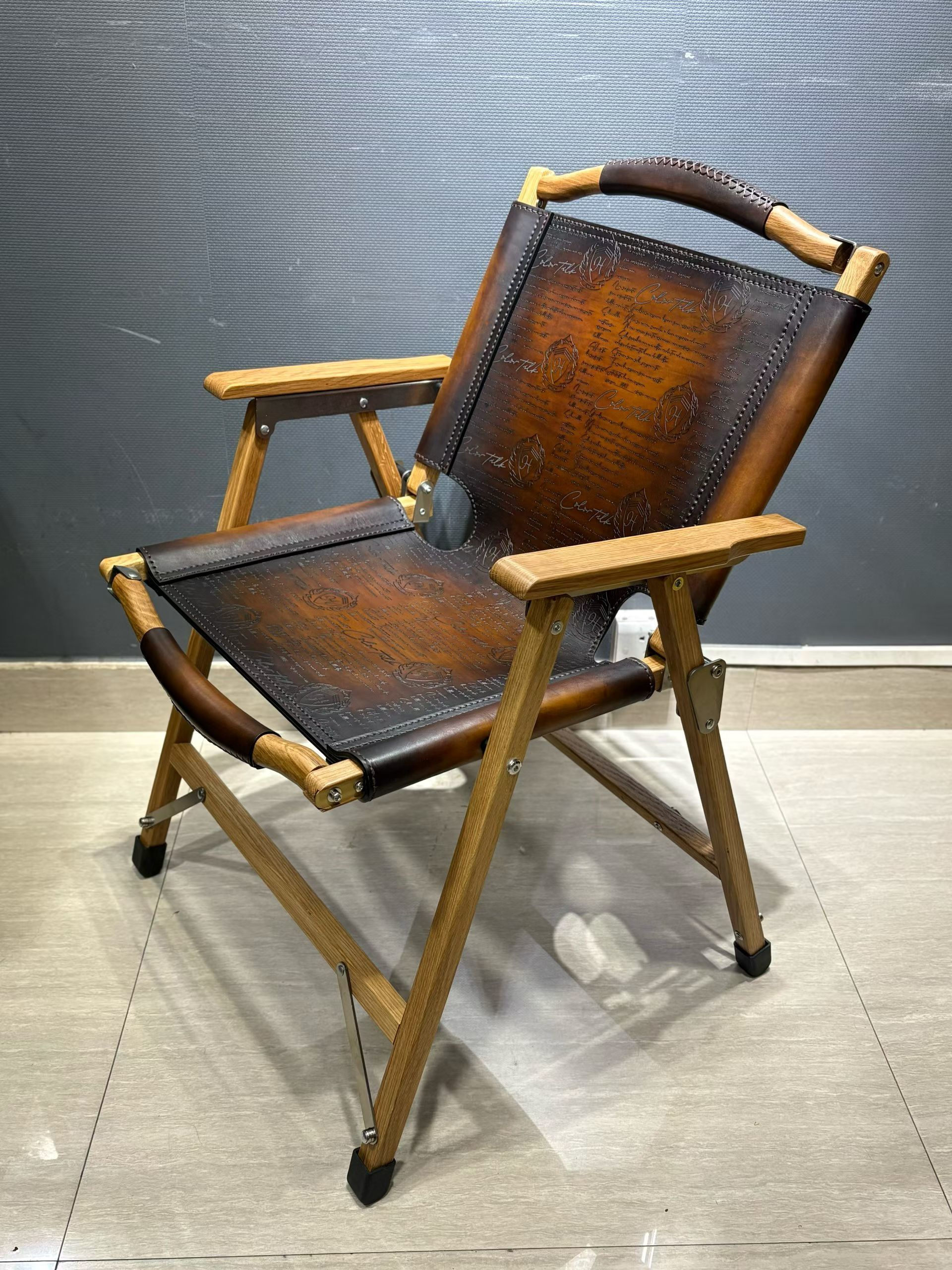 Berluti Metro wooden folding chair with a brown leather seat and backrest.