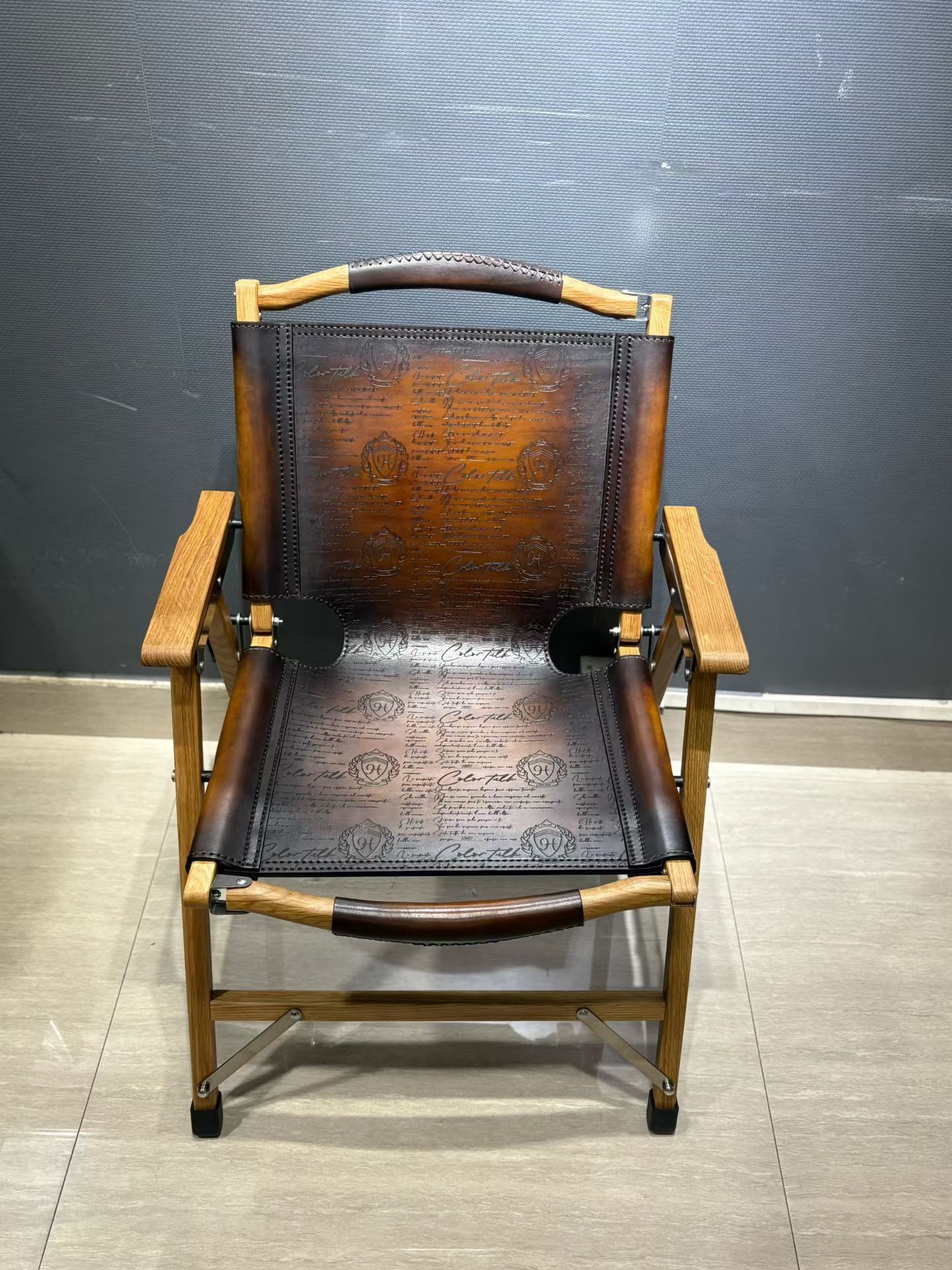 Berluti Metro wooden folding chair with a brown leather seat and backrest.