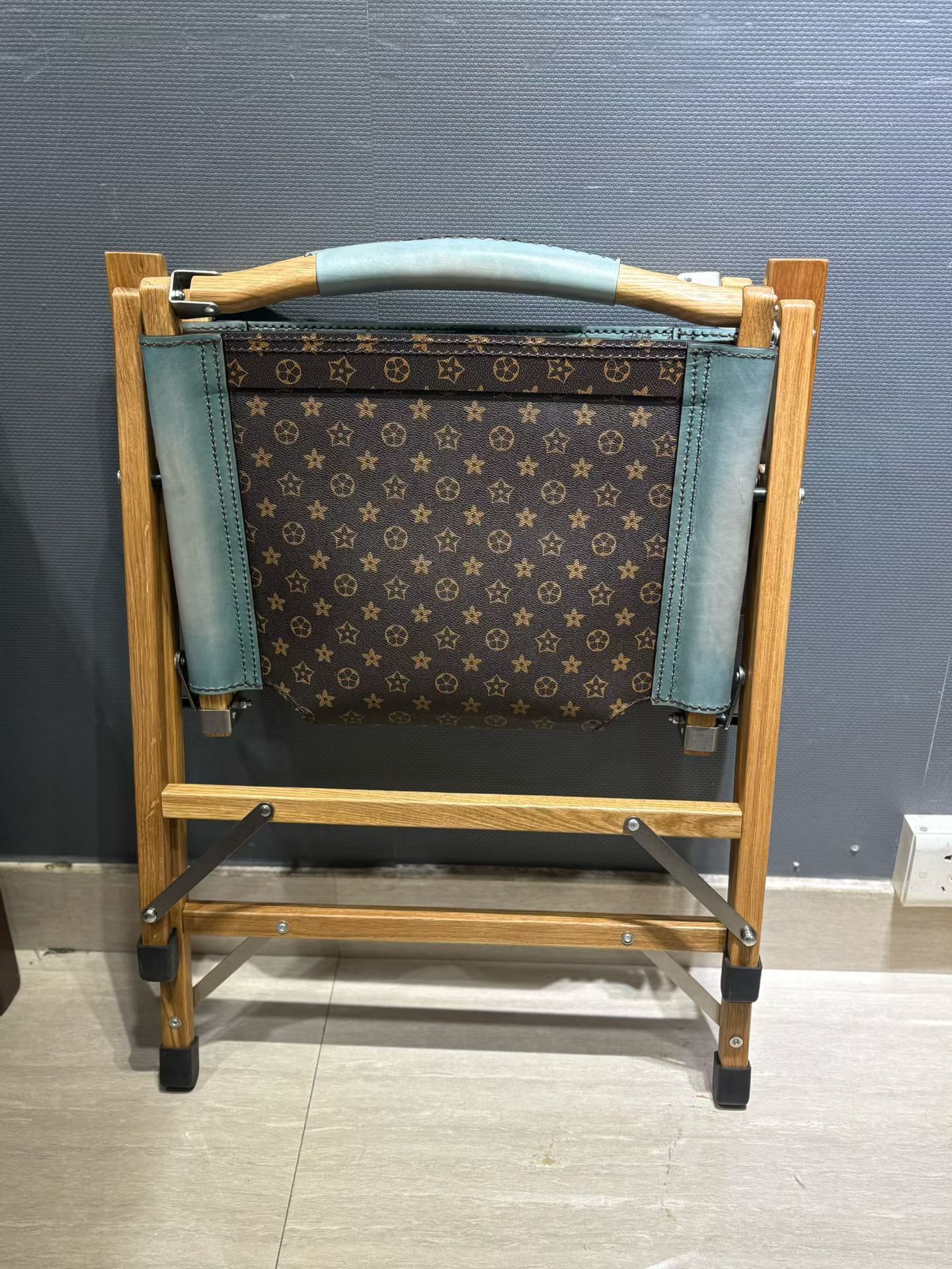 Berluti Metro wooden folding chair with a brown leather seat and backrest.