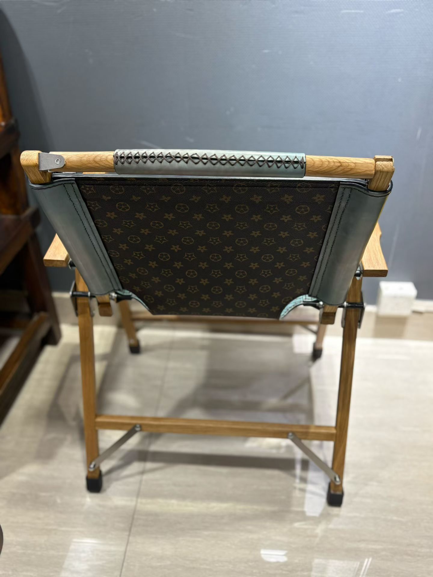 Berluti Metro wooden folding chair with a brown leather seat and backrest.