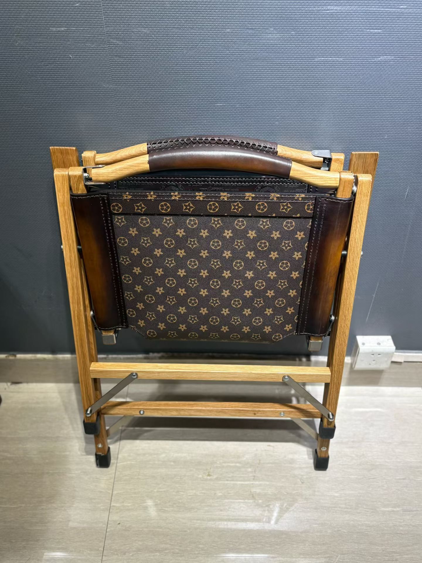 Berluti Metro wooden folding chair with a brown leather seat and backrest.