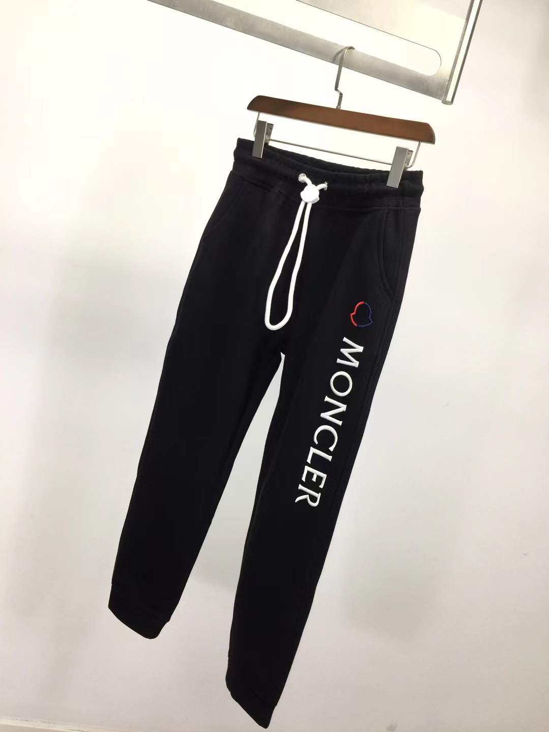 Moncler Black sweatpants with a white vertical logo print on the leg