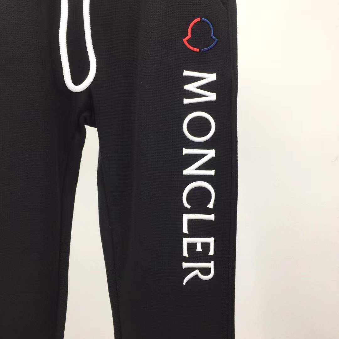 Moncler Black sweatpants with a white vertical logo print on the leg