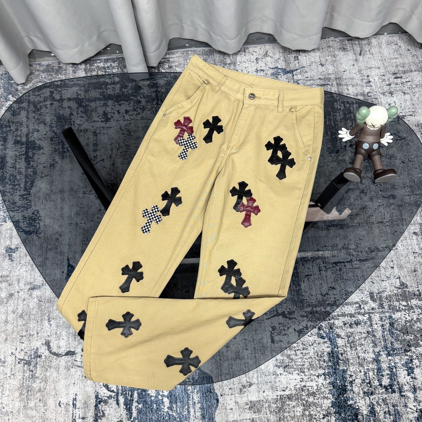 Chrome Hearts cross patch beige jeans.