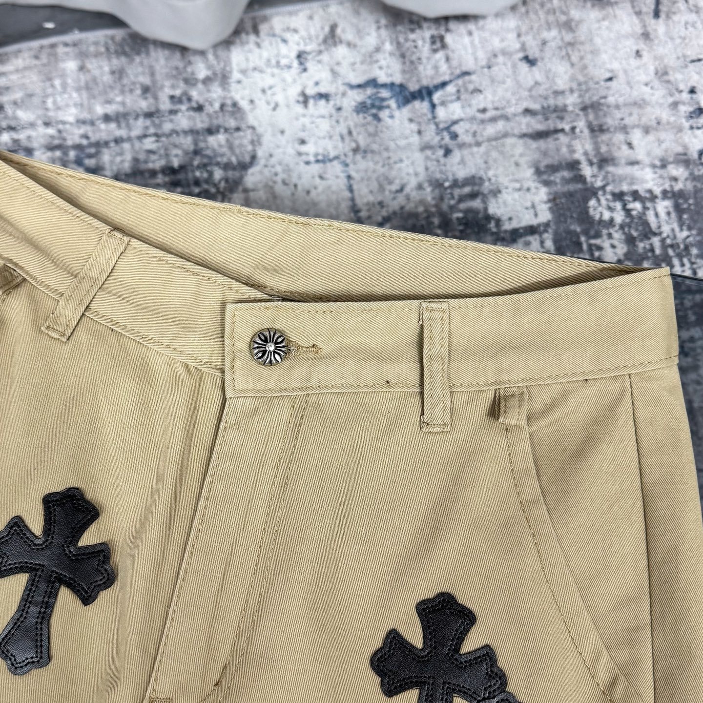 Chrome Hearts cross patch beige jeans.