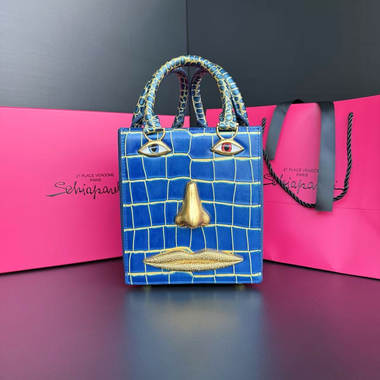 Schiaparelli Face Bag in blue calfskin with crocodile-effect embossing and anatomical jewels in enamel and hammered gold-plated brass.