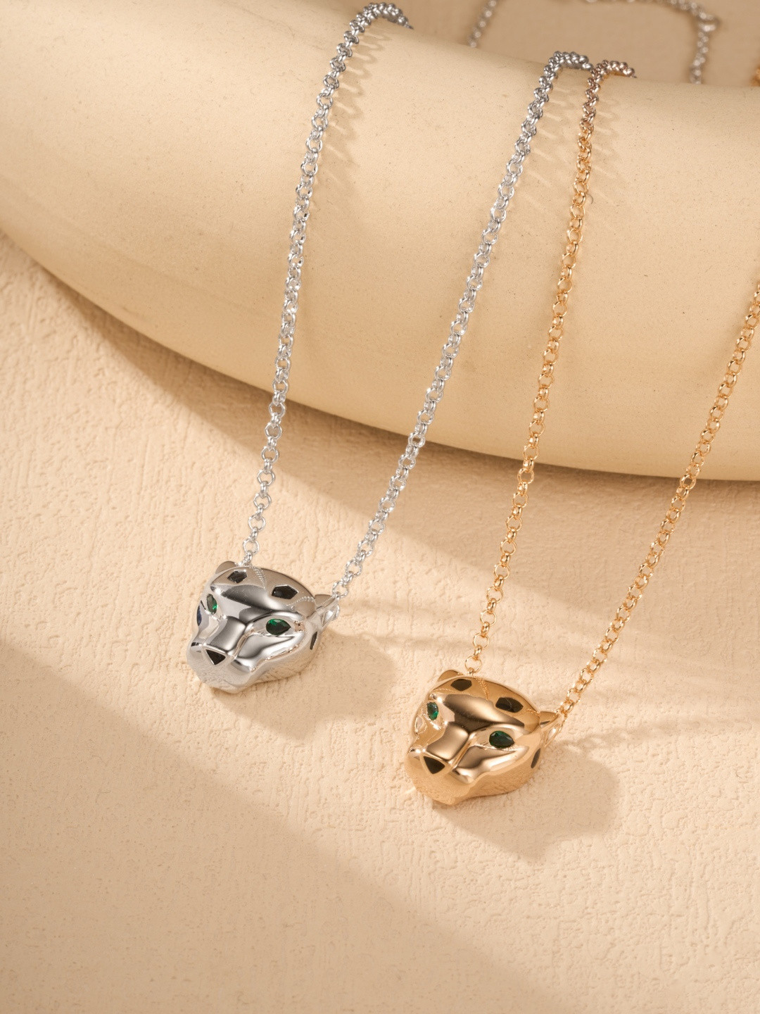 Cartier Panthère-style pendant necklaces featuring a silver-tone and gold-tone finish with green gemstone eyes.