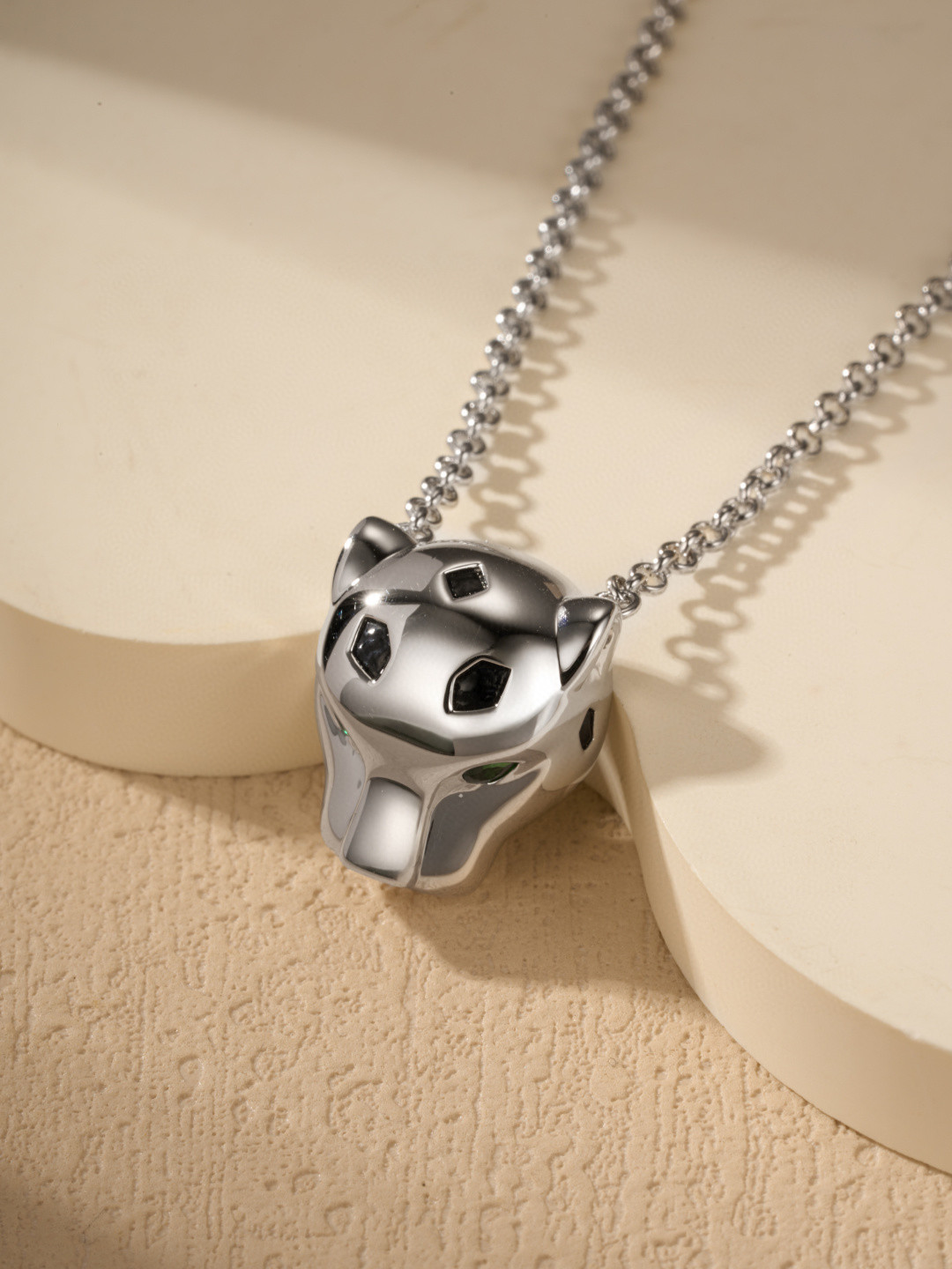 Cartier Panthère-style pendant necklaces featuring a silver-tone and gold-tone finish with green gemstone eyes.