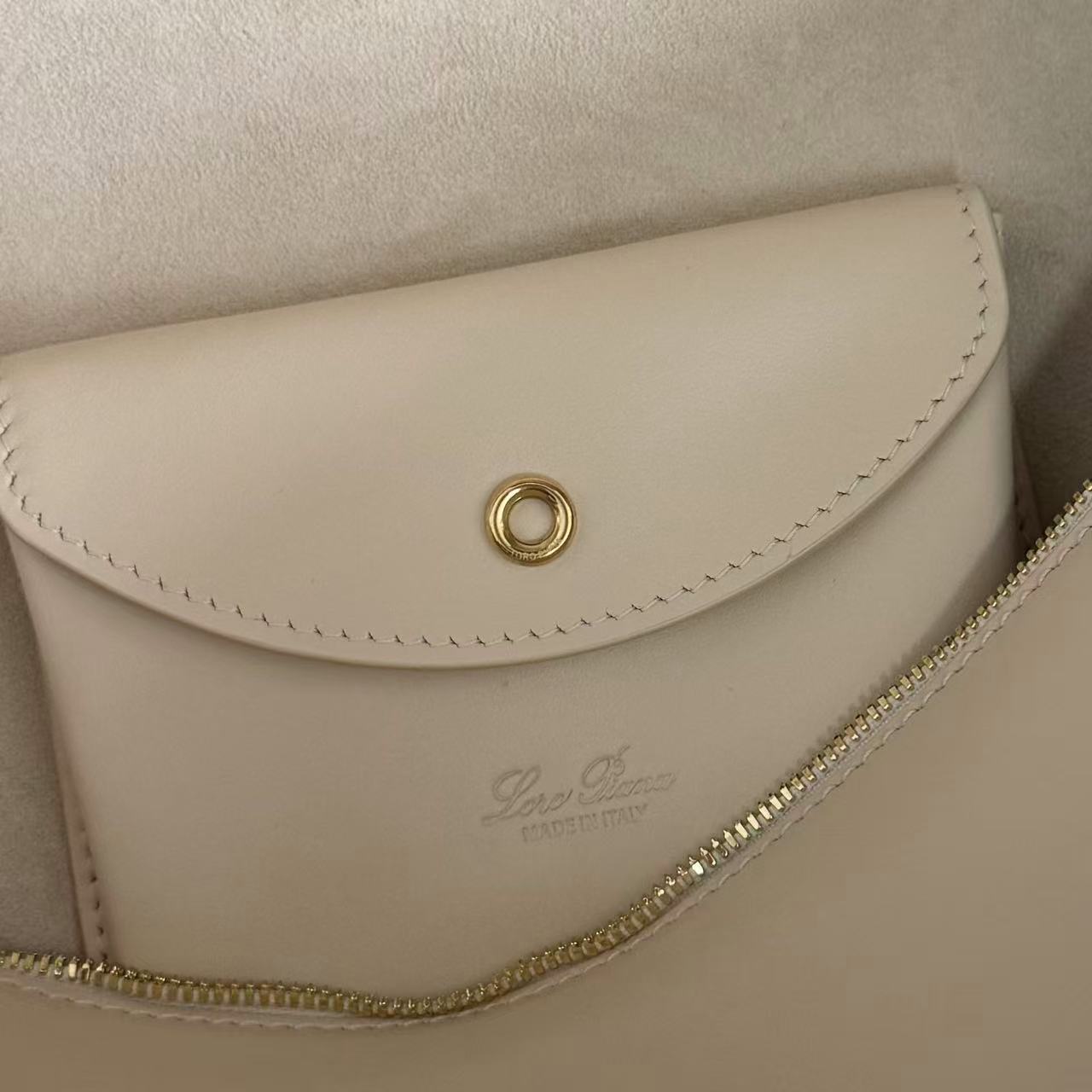 Loro Piana Extra Bag likely the L27 size in a light leather color, featuring a structural shape with double zippers and iconic charms