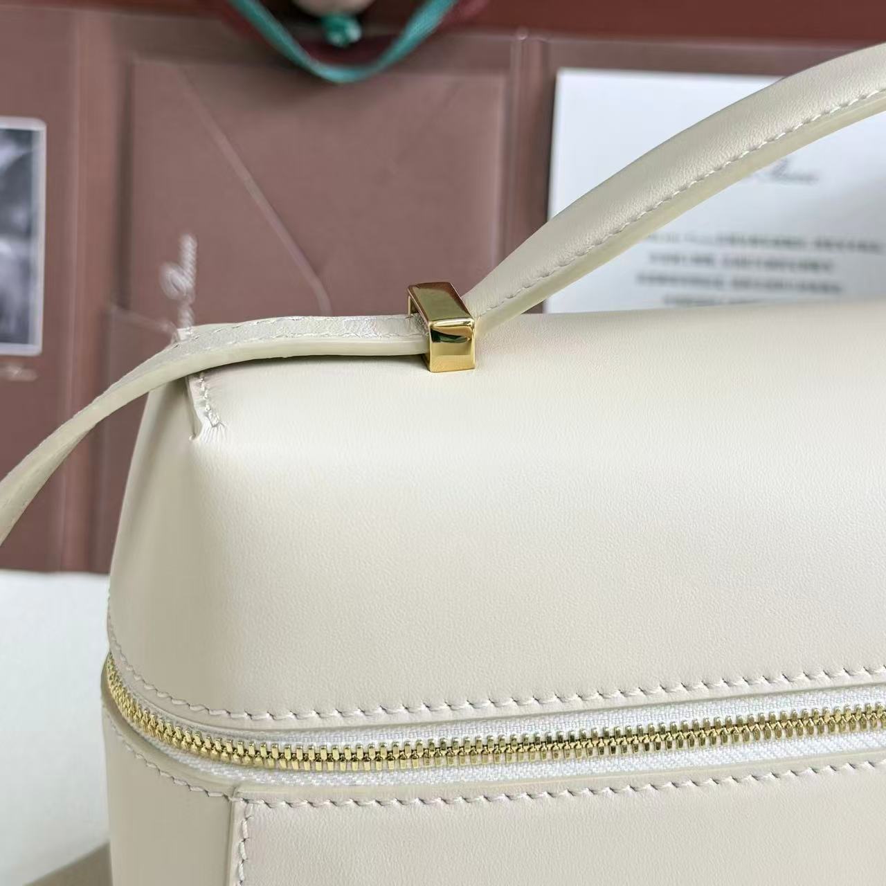 Loro Piana Extra Bag likely the L27 size in a light leather color, featuring a structural shape with double zippers and iconic charms