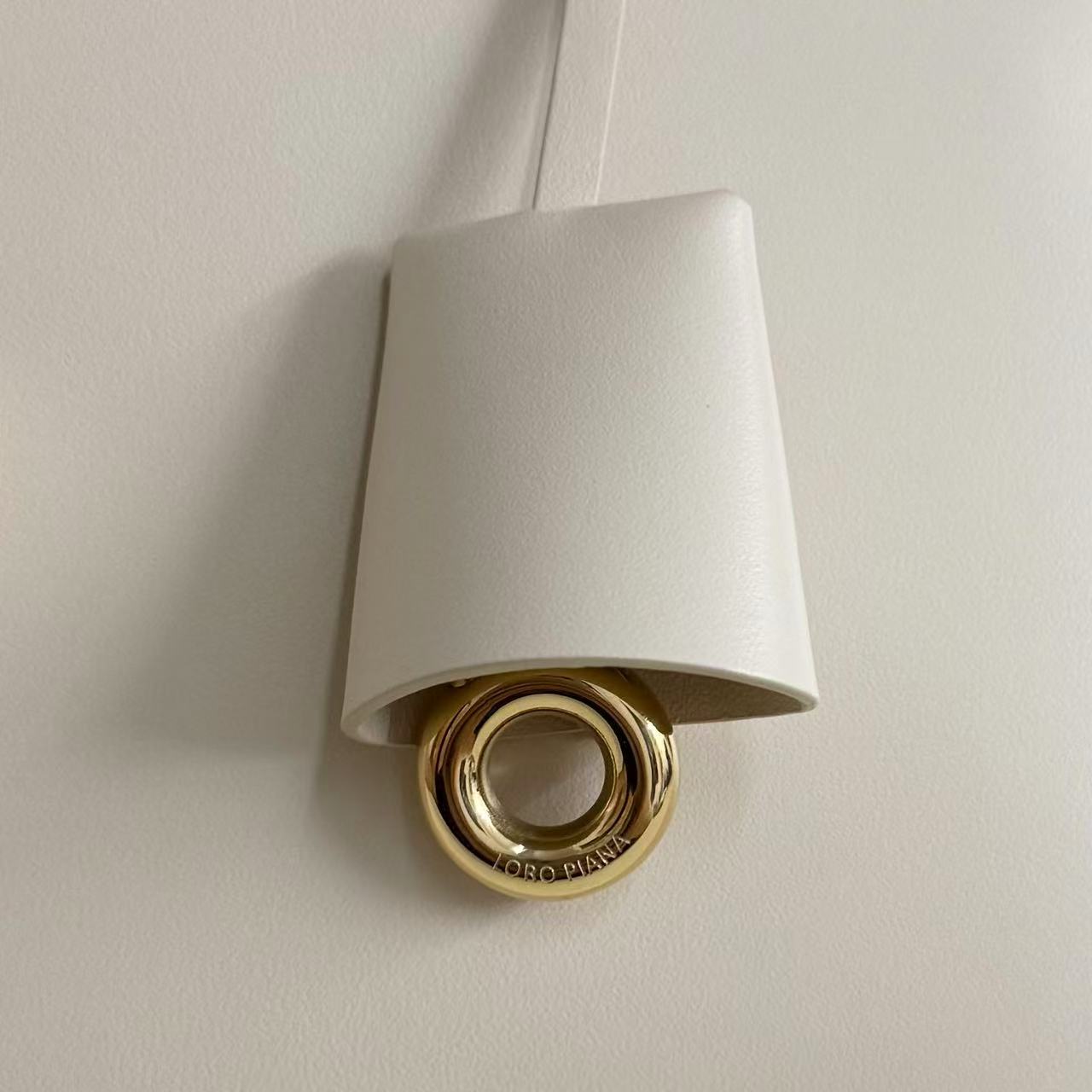 Loro Piana Extra Bag likely the L27 size in a light leather color, featuring a structural shape with double zippers and iconic charms