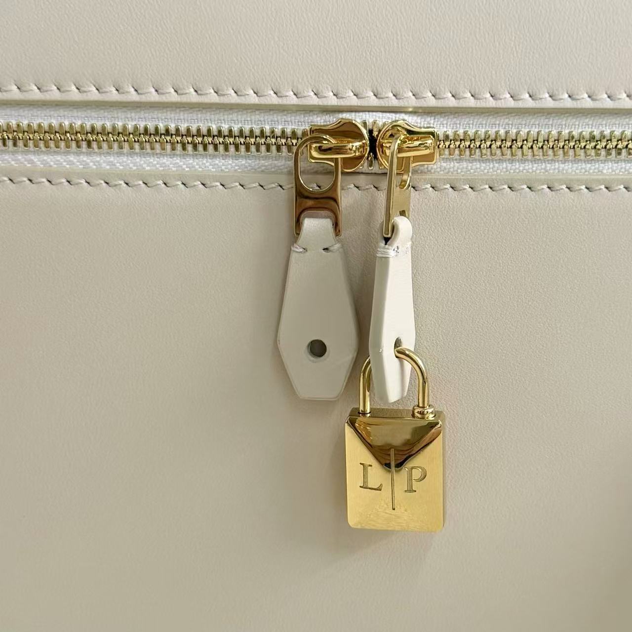 Loro Piana Extra Bag likely the L27 size in a light leather color, featuring a structural shape with double zippers and iconic charms