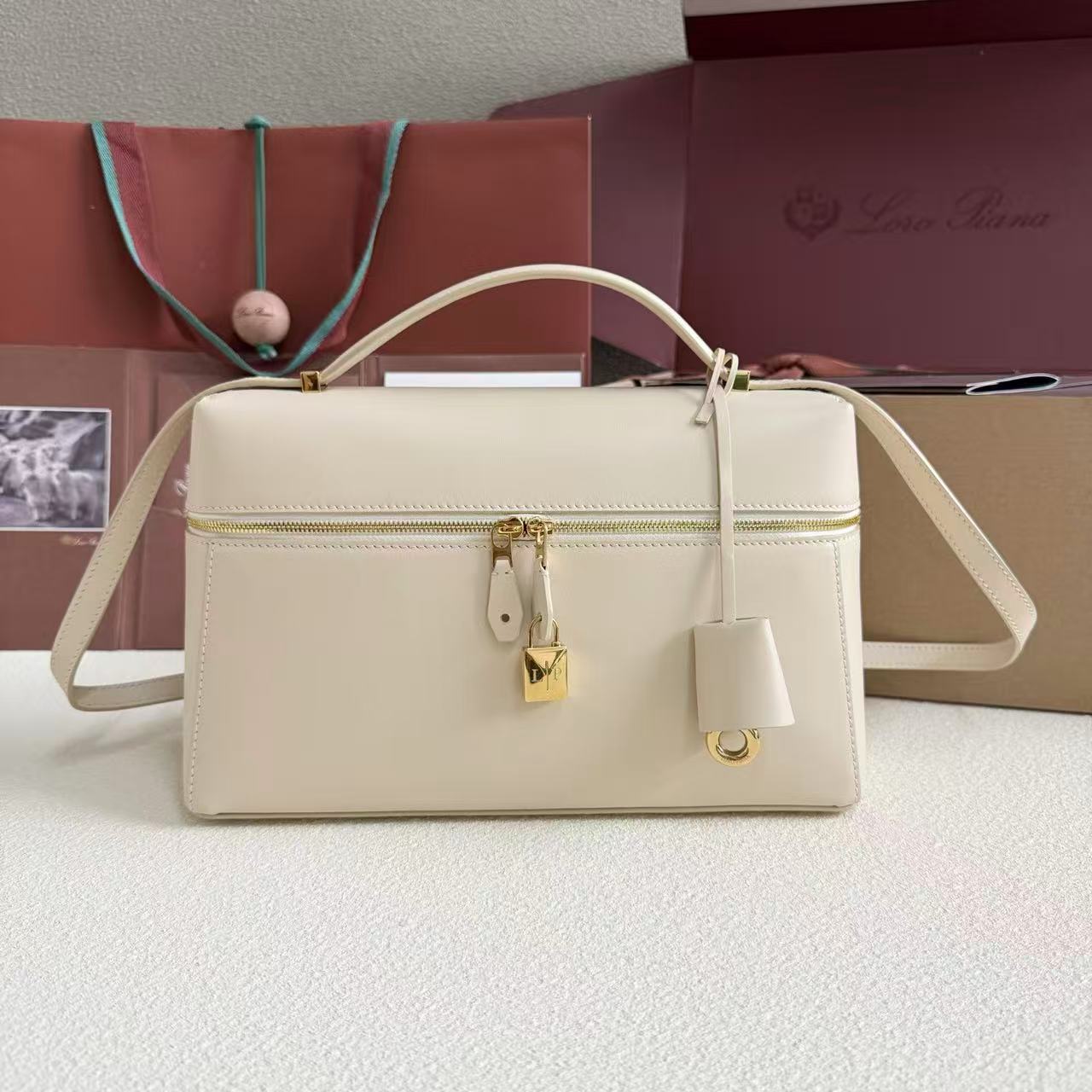 Loro Piana Extra Bag likely the L27 size in a light leather color, featuring a structural shape with double zippers and iconic charms