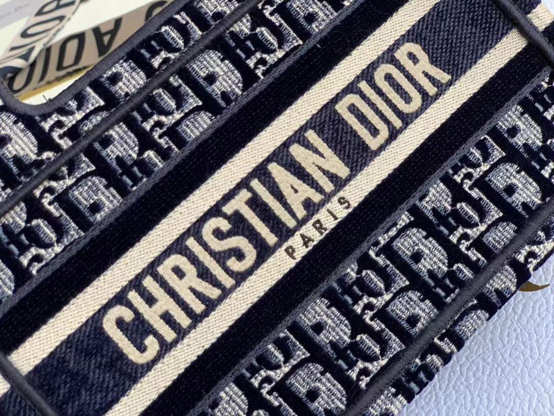 Christian Dior Mini Book Tote in Blue Dior Oblique Embroidery, which features the signature logo on the front