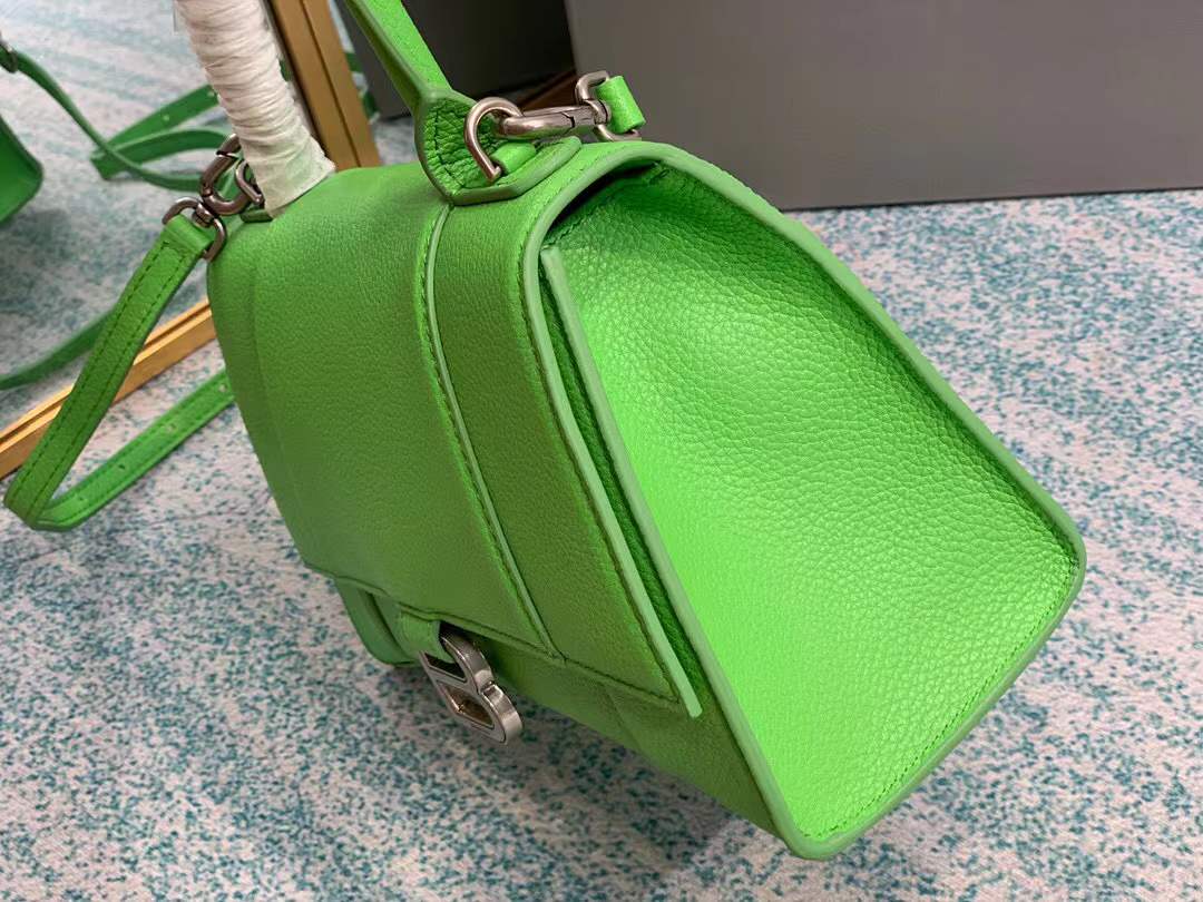 Balenciaga Hourglass bag, a structured leather handbag featuring a curved base and a signature "B" logo closure.