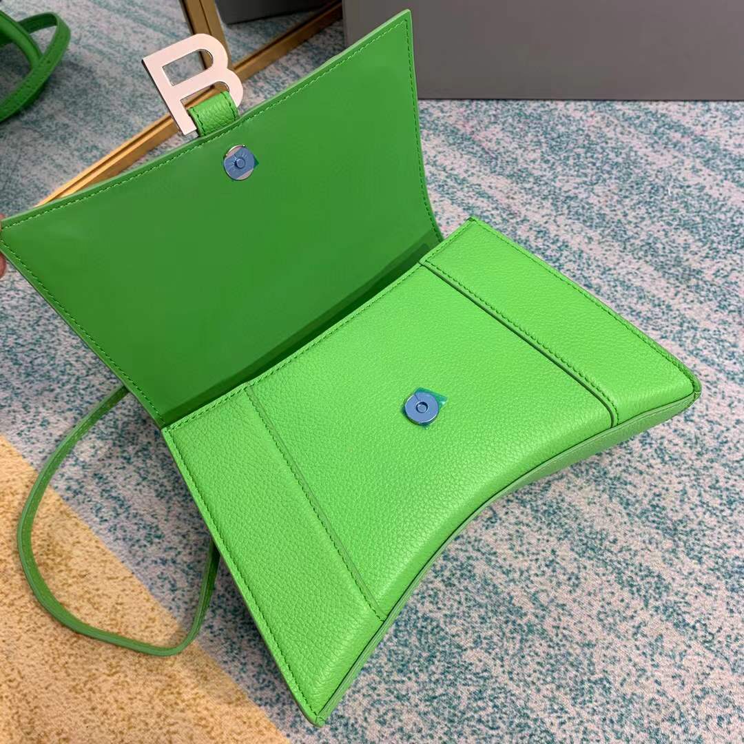 Balenciaga Hourglass bag, a structured leather handbag featuring a curved base and a signature "B" logo closure.