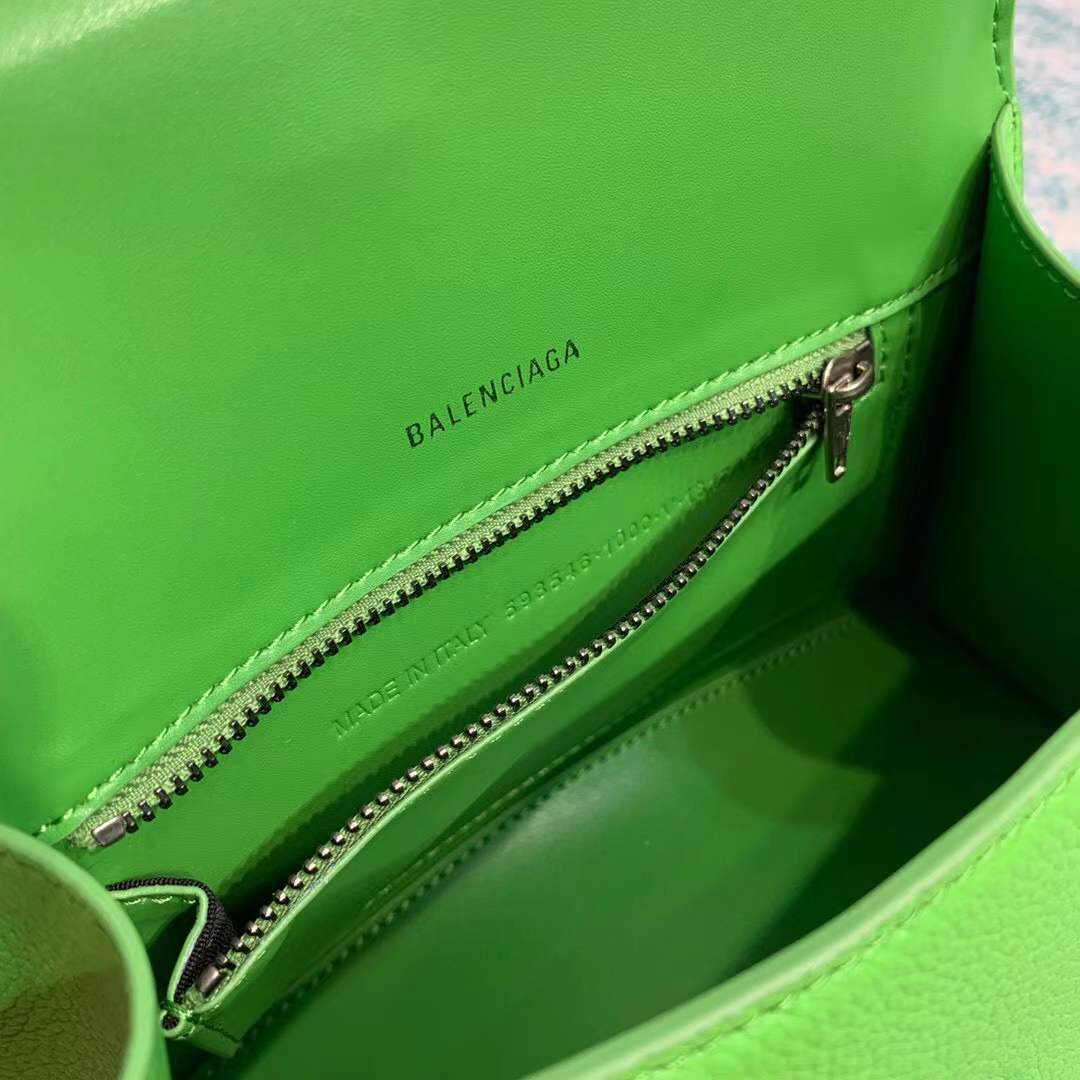 Balenciaga Hourglass bag, a structured leather handbag featuring a curved base and a signature "B" logo closure.