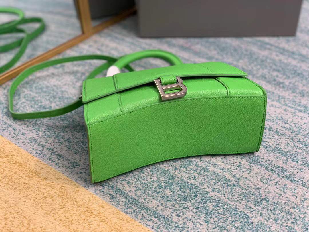 Balenciaga Hourglass bag, a structured leather handbag featuring a curved base and a signature "B" logo closure.