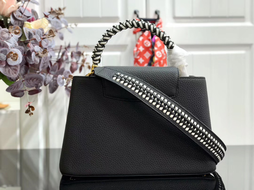 LV Capucines handbag, likely in the BB size, is crafted from black Taurillon leather and features a distinctive jewelry-inspired chain top handle and signature LV initials