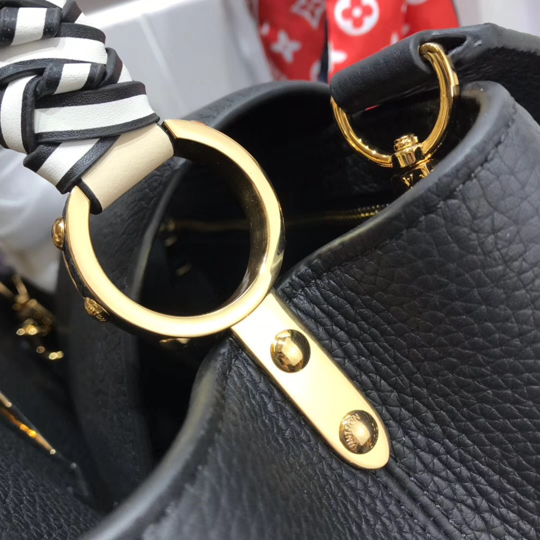LV Capucines handbag, likely in the BB size, is crafted from black Taurillon leather and features a distinctive jewelry-inspired chain top handle and signature LV initials
