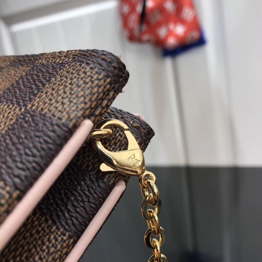 LV Damier Ebene Double Zip Pochette in Pink is a versatile crossbody bag crafted from the iconic checkerboard canvas, featuring distinctive pink leather trim and a prominent LV signature.
