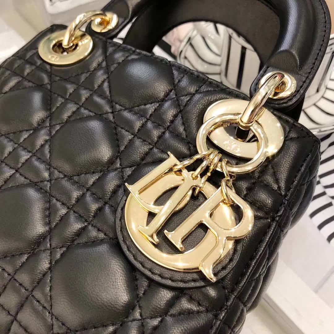 christian dior black quilted lambskin leather Lady Dior bag featuring distinctive Cannage stitching and pale gold-finish metal D.I.O.R. charms