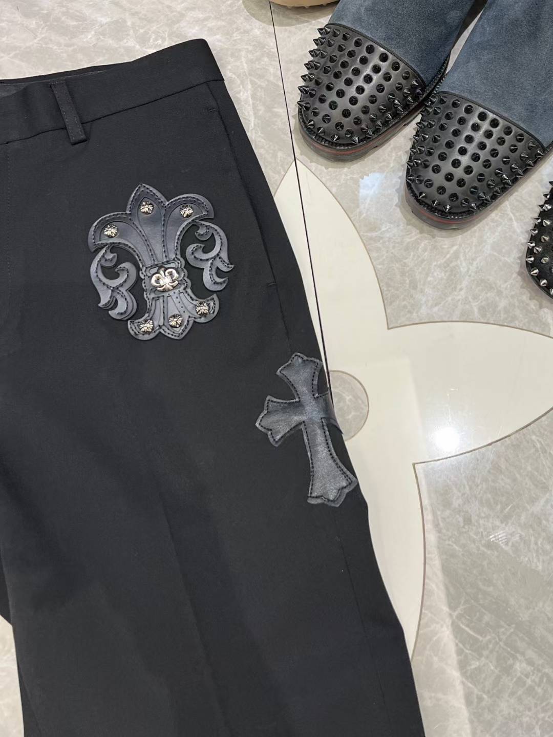 chrome hearts black trousers feature decorative patches and embroidery resembling a luxury designer pair such as those from Philipp Plein