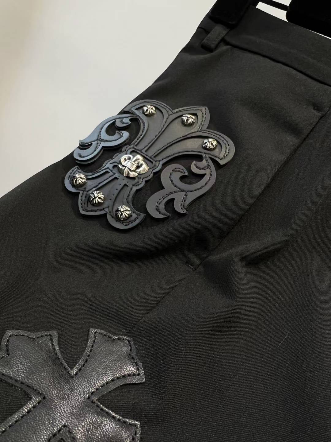 chrome hearts black trousers feature decorative patches and embroidery resembling a luxury designer pair such as those from Philipp Plein