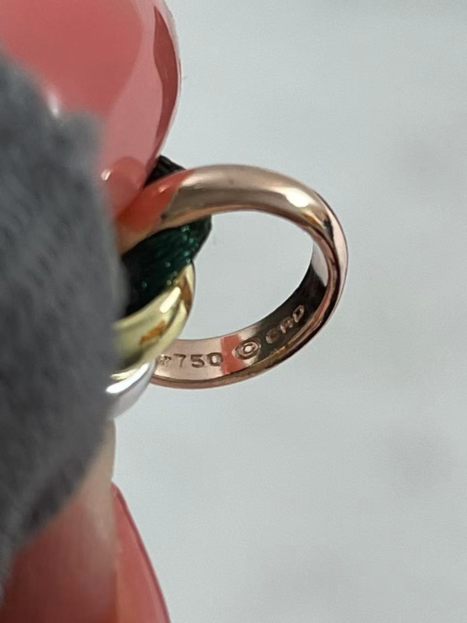 Cartier Trinity bracelet featuring three interlaced bands on a green cord