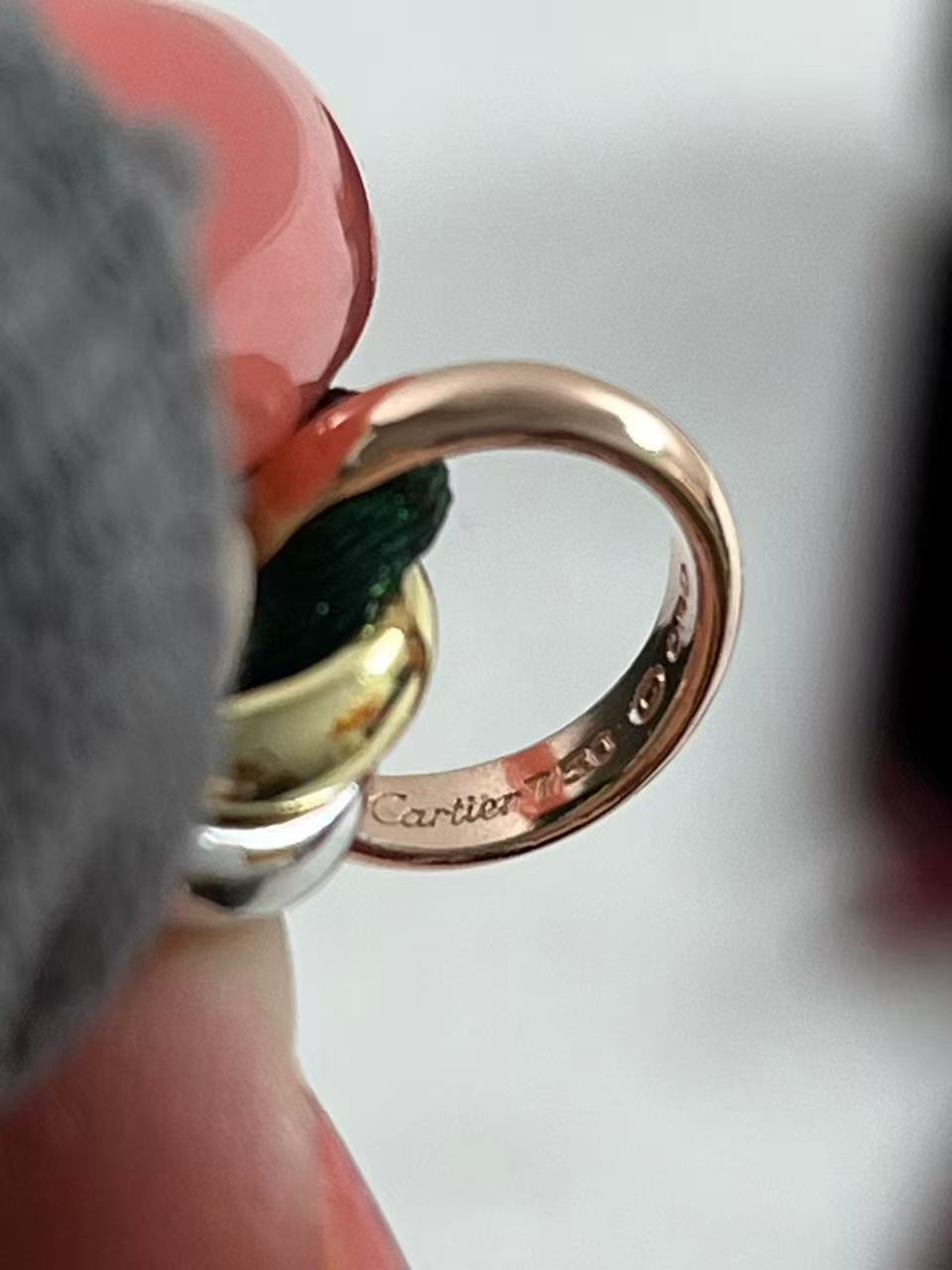 Cartier Trinity bracelet featuring three interlaced bands on a green cord