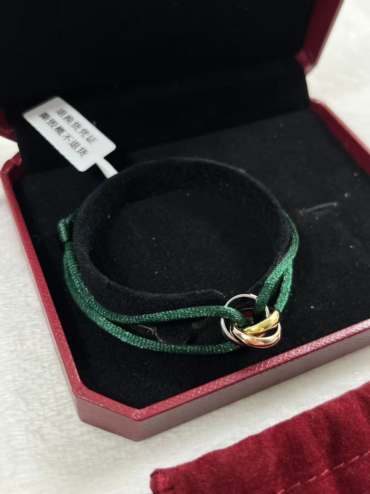 Cartier Trinity bracelet featuring three interlaced bands on a green cord