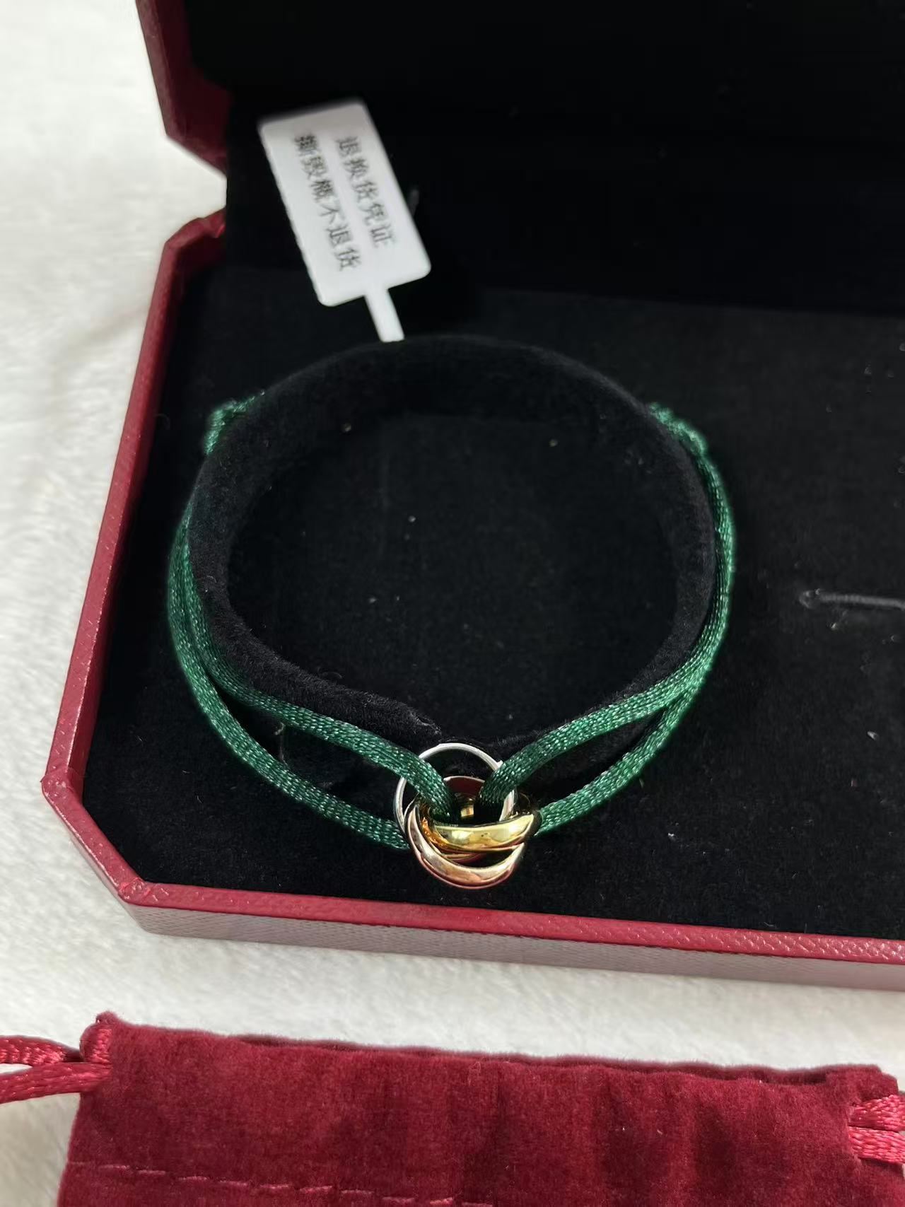 Cartier Trinity bracelet featuring three interlaced bands on a green cord