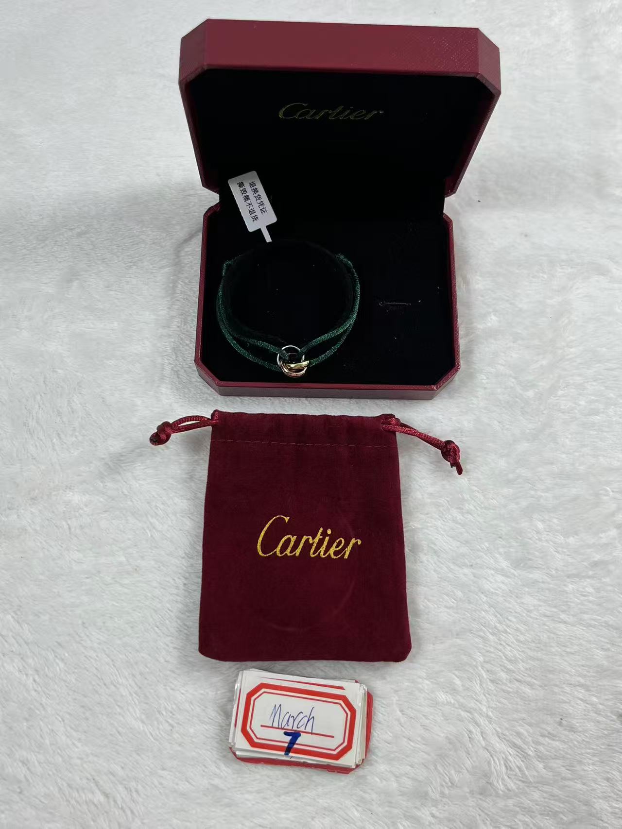 Cartier Trinity bracelet featuring three interlaced bands on a green cord