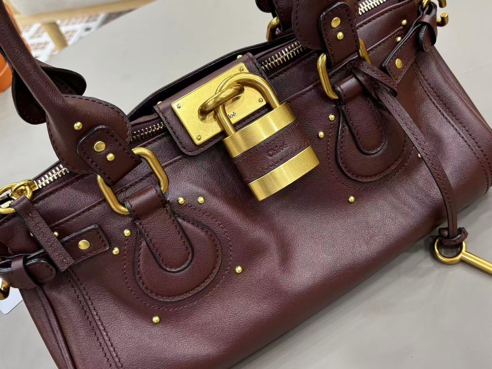 Chloe Paddington bag in Crafty Brown featuring the signature oversized gold padlock, dual top handles, and grained buffalo leather
