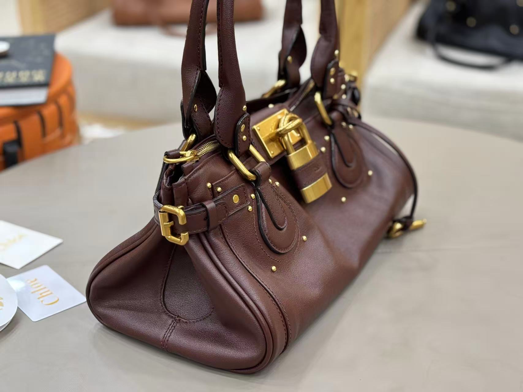 Chloe Paddington bag in Crafty Brown featuring the signature oversized gold padlock, dual top handles, and grained buffalo leather