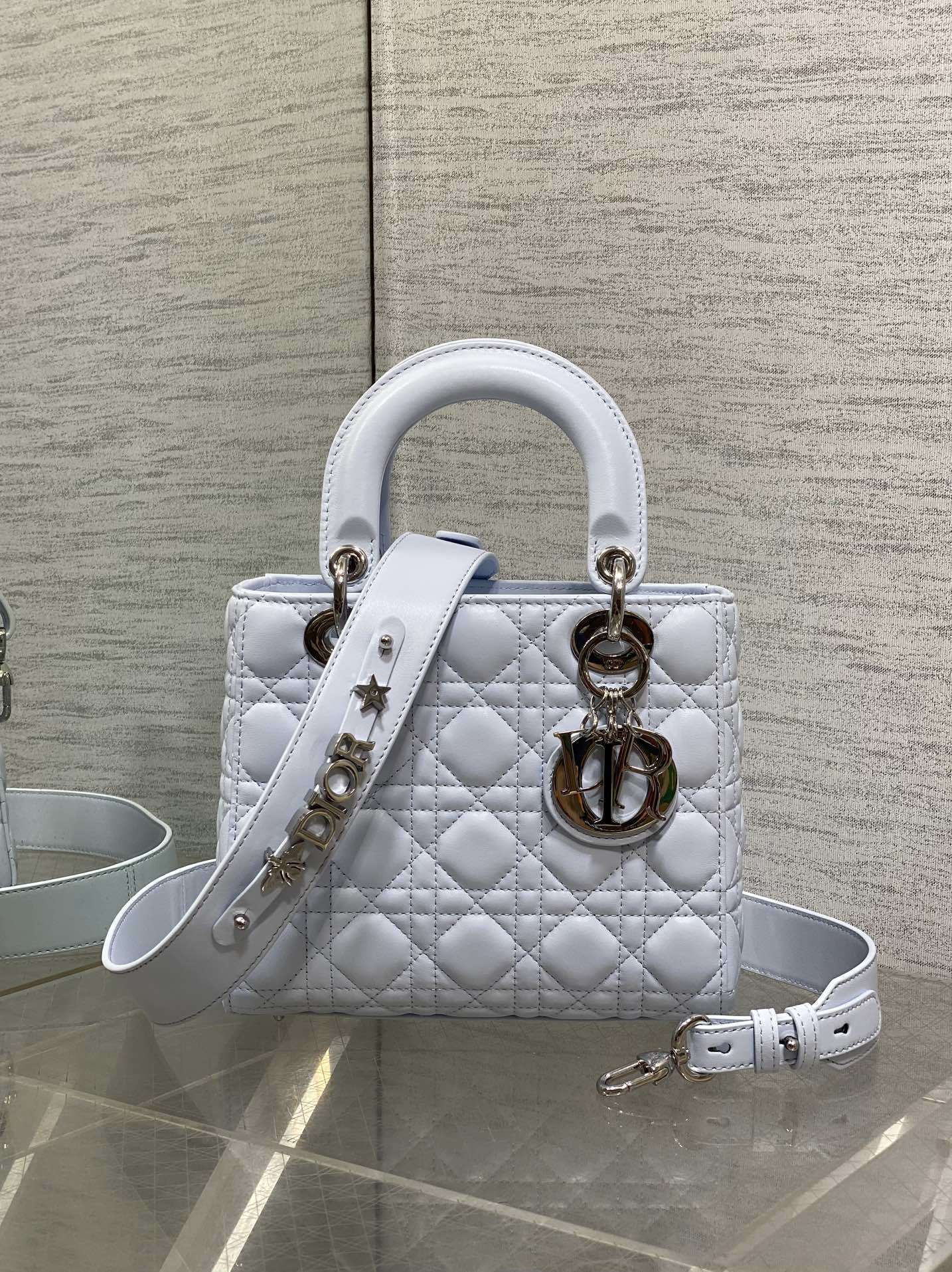 Dior Small Lady Dior Bag in white lambskin, featuring the iconic Cannage quilting pattern and customizable shoulder strap.