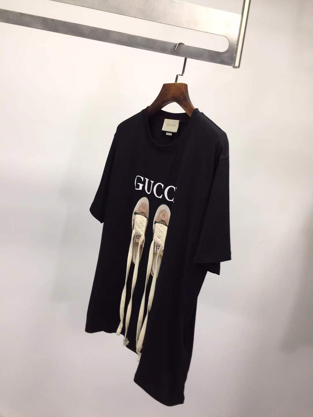 Gucci black t-shirt featuring a printed graphic of shoes with hanging shoelaces