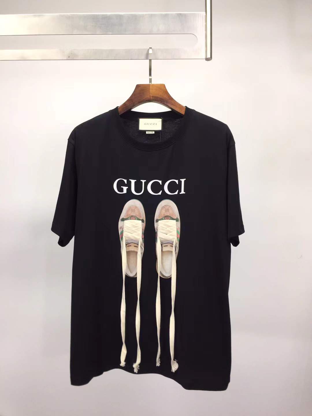 Gucci black t-shirt featuring a printed graphic of shoes with hanging shoelaces
