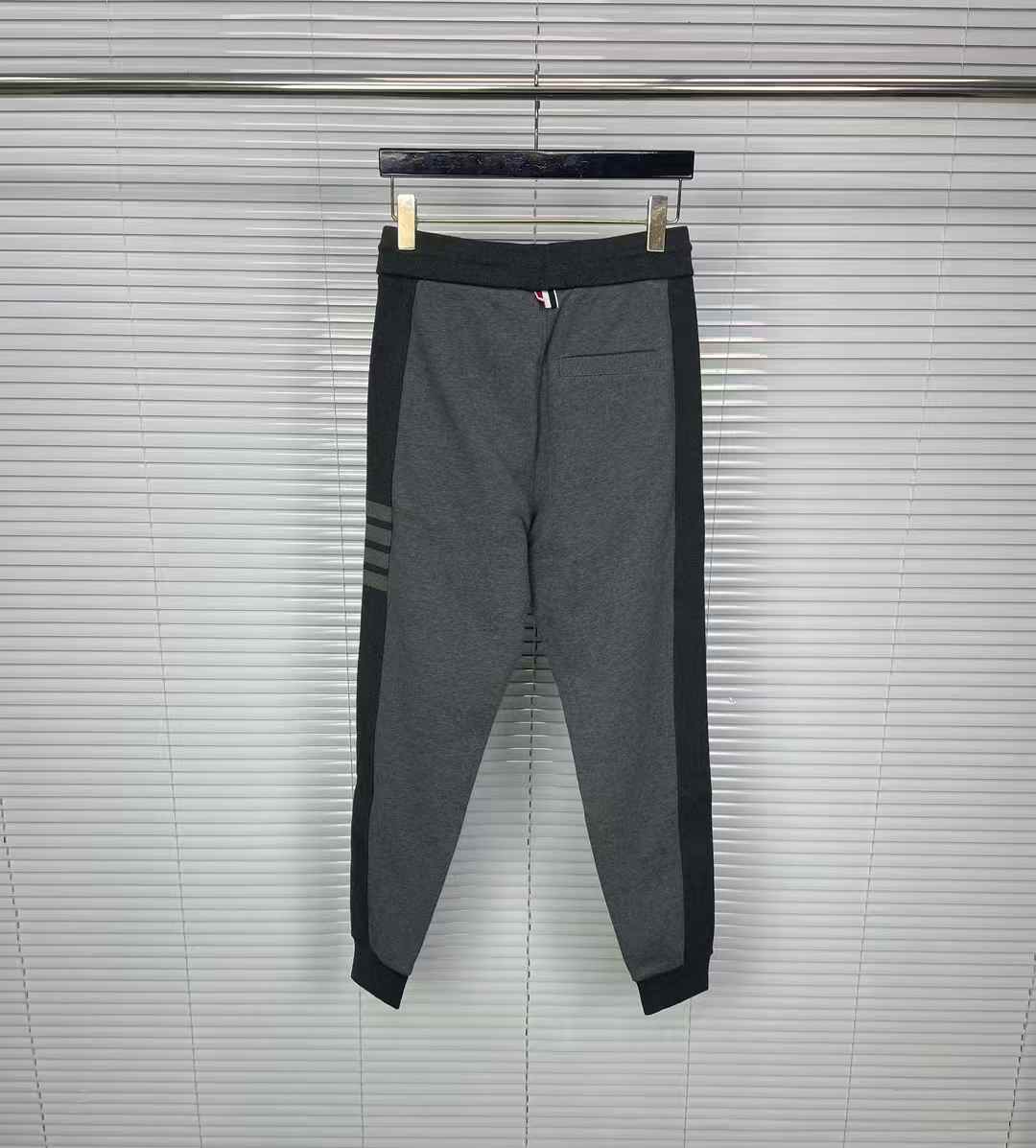 Thom Browne men's gray cotton jersey sweatpants featuring a color-block design and the signature 4-bar stripe detail on the side