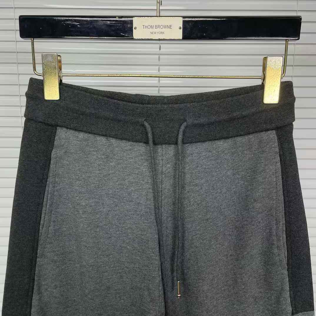 Thom Browne men's gray cotton jersey sweatpants featuring a color-block design and the signature 4-bar stripe detail on the side