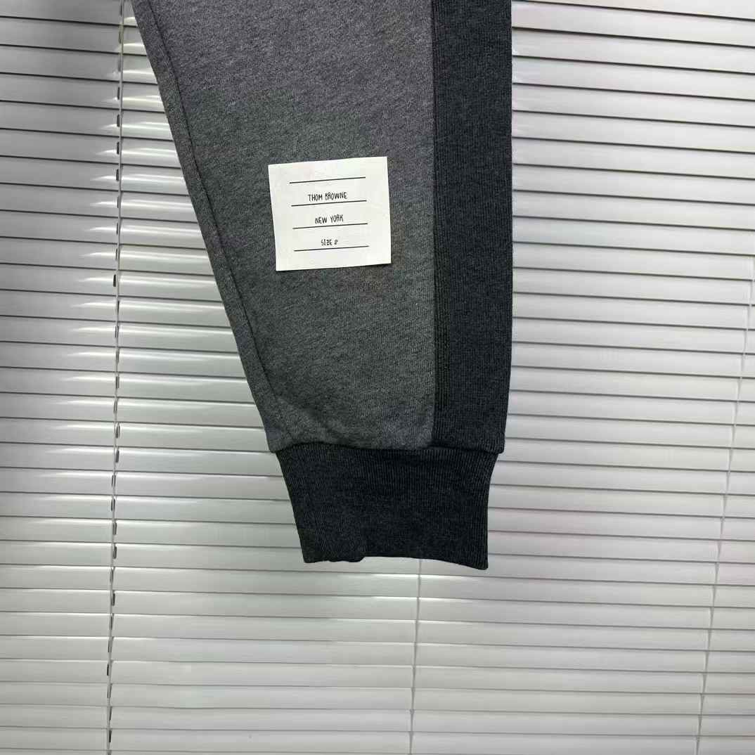Thom Browne men's gray cotton jersey sweatpants featuring a color-block design and the signature 4-bar stripe detail on the side